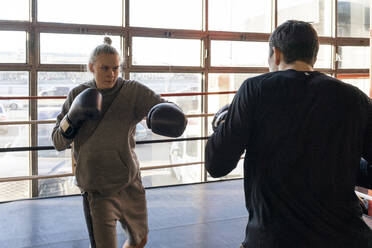Female boxer sparring with her coach in gym - VPIF02082