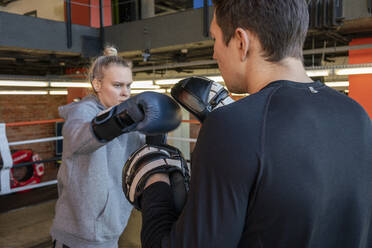 Weibliche Boxerin beim Sparring mit ihrem Trainer im Fitnessstudio - VPIF02083