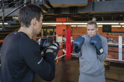 Weibliche Boxerin beim Sparring mit ihrem Trainer im Fitnessstudio - VPIF02085