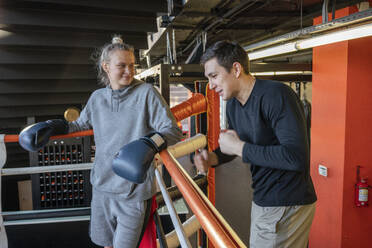 Trainer im Gespräch mit einer Boxerin im Fitnessstudio - VPIF02087