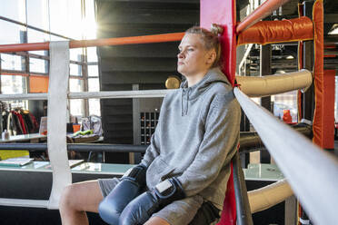 Weiblicher Boxer in der Turnhalle in der Ringecke sitzend - VPIF02089