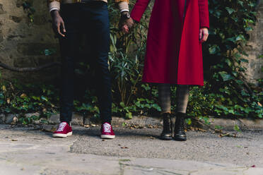 Low section of couple standing hand in hand outdoors - FMOF00868