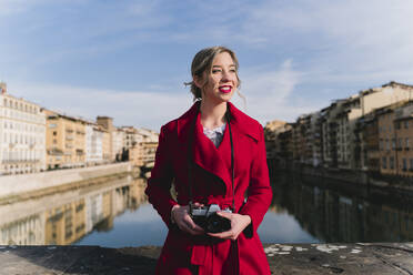 Junge Frau mit einer Kamera auf einer Brücke über dem Arno, Florenz, Italien - FMOF00878