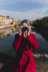 Junge Frau beim Fotografieren auf einer Brücke über dem Fluss Arno, Florenz, Italien - FMOF00881