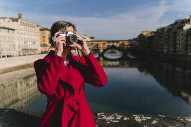 Junge Frau beim Fotografieren auf einer Brücke über dem Fluss Arno, Florenz, Italien - FMOF00882
