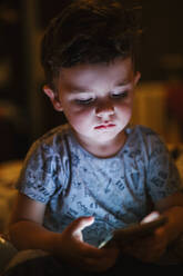 Porträt eines Kleinkindes, das auf sein Smartphone schaut - LJF01369