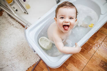 Porträt eines kleinen Jungen in der Badewanne, der die Zunge herausstreckt - LJF01375