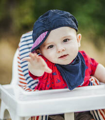 Porträt eines kleinen Jungen mit Mütze und Schal im Hochstuhl sitzend - LJF01381