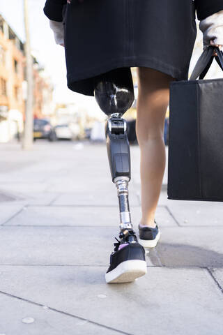 Low section of woman with leg prosthesis walking in the city stock photo