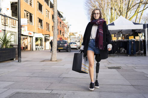 Portrait of confident young woman with leg prosthesis walking in the city - FBAF01286