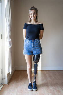 Porträt einer lächelnden jungen Frau mit Beinprothese - FBAF01294