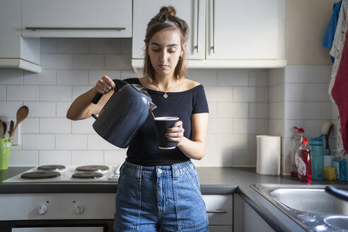 Young woman preparing an instant coffee in kitchen at home - FBAF01297