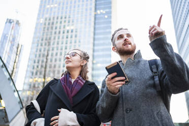 Young couple with cell phone in the city looking around, London, UK - FBAF01301