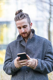 Young man using cell phone in the city - FBAF01306