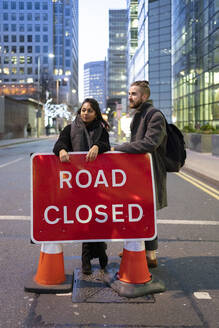 Young couple standing on a closed road in the city, London, UK - FBAF01311