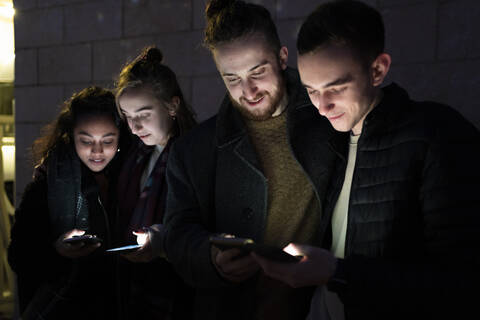 Friends looking at illuminated smartphones in the dark stock photo