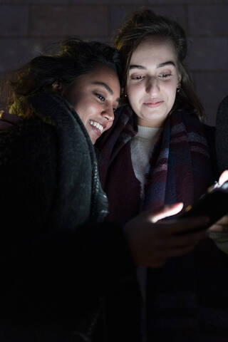 Friends looking at illuminated smartphones in the dark stock photo