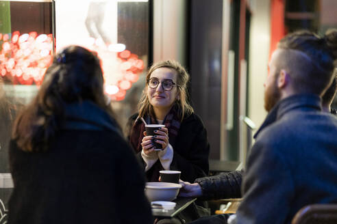 Friends meeting at a sidewalk cafe in the city - FBAF01320