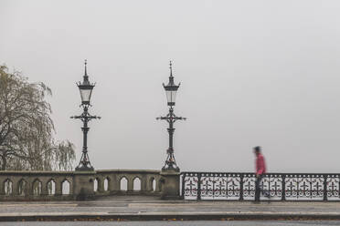 Germany, Hamburg, Pedestrian walking across Schwanenwikbrucke bridge during foggy weather - KEBF01481