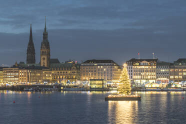 Deutschland, Hamburg, Beleuchtete Alstertanne in der Abenddämmerung mit Jungfernstiegpromenade und Nikolauskirche im Hintergrund - KEBF01484