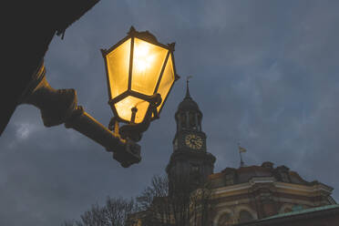 Deutschland, Hamburg, Low angle view of street light glowing against tower of Saint Michaels Church at night - KEBF01490