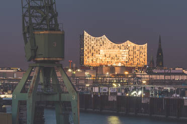 Germany, Hamburg, Harbor crane and Elbphilharmonie hall at dusk - KEBF01503