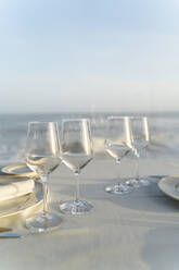 Spain, Empty wineglasses on set restaurant table with sea in background - AFVF05457