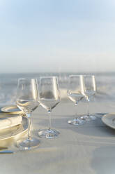 Spanien, Leere Weingläser auf gedecktem Restauranttisch mit Meer im Hintergrund - AFVF05457