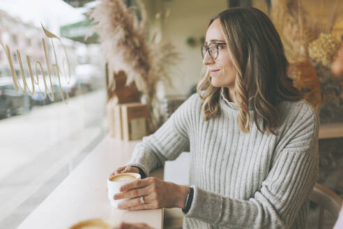 Blonde Frau trinkt Kaffee in einem Cafe - CMSF00110