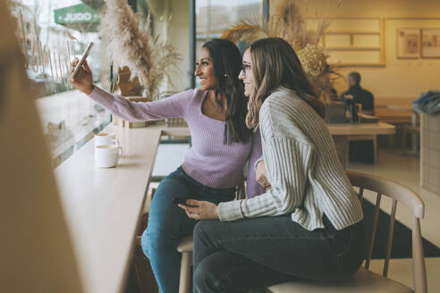 Zwei Frauen machen ein Selfie in einem Cafe - CMSF00112