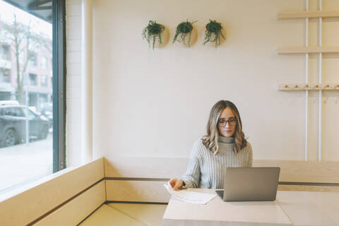 Blonde Frau mit Laptop in einem Café, lizenzfreies Stockfoto