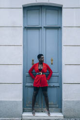 Junge Frau mit rotem Blazer vor blauer Tür - MPPF00572