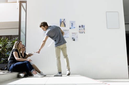 Three young architects working by a whiteboard, discussing design ideas. - CUF54853