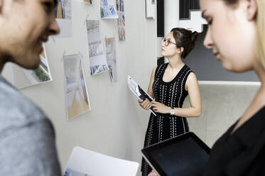 Drei junge Architekten stehen an einem Whiteboard und diskutieren über Entwurfsideen. - CUF54856