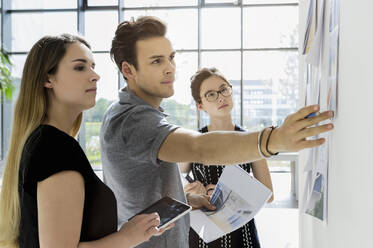 Drei junge Architekten stehen an einem Whiteboard und diskutieren über Entwurfsideen. - CUF54858