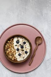 Schale mit Müsli und Blaubeeren auf Joghurt, Holzteelöffel - ISF23867