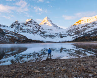 A man taking in the view across a lake to the panoramic view of Mount Assiniboine, Great Divide, Canadian Rockies, Alberta, Canada - ISF23884