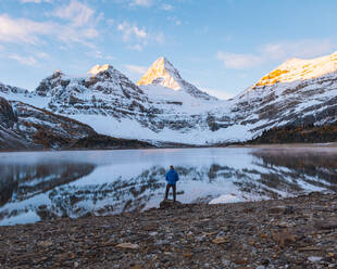 Ein Mann genießt den Blick über einen See auf das Panorama des Mount Assiniboine, Great Divide, Kanadische Rockies, Alberta, Kanada - ISF23884