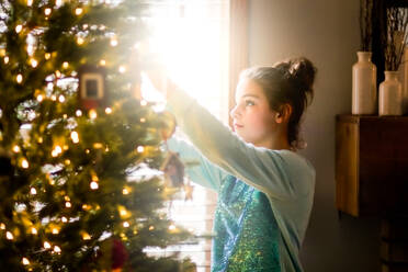 Junges Mädchen schmückt den Weihnachtsbaum zu Hause - ISF23887
