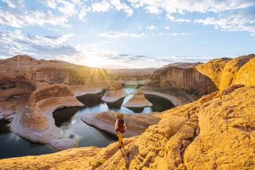 Rucksacktourist bei Sonnenaufgang, Reflection Canyon, Lake Powell, Utah, USA - ISF23919