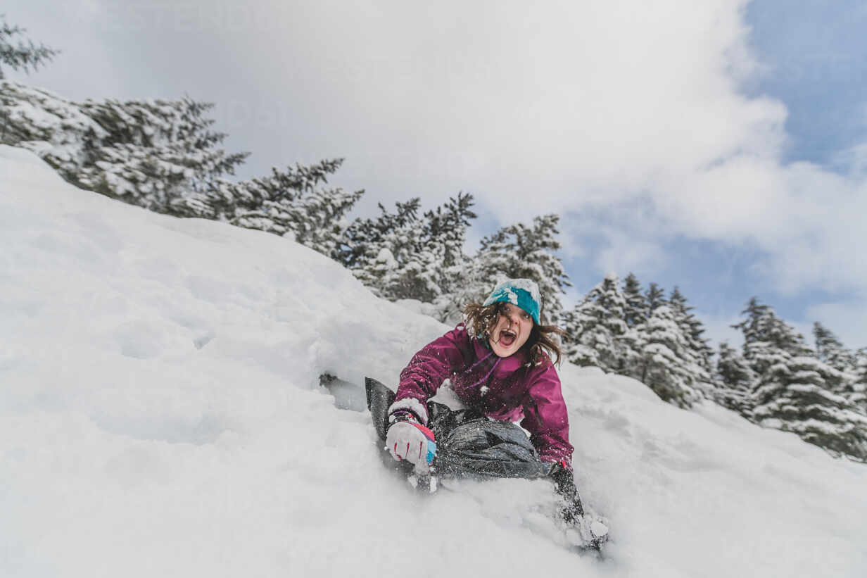 Woman sliding down a snow-covered slope in a Canadian forest. stock photo