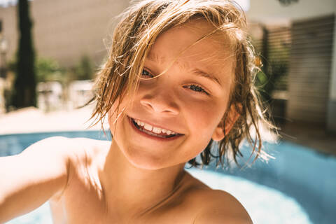 Porträt eines lächelnden Jungen am Swimmingpool eines Resorts, lizenzfreies Stockfoto