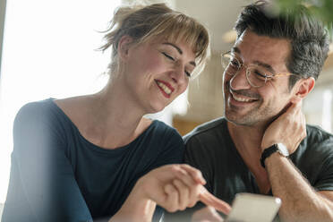 Happy couple using smartphone at home - KNSF07665