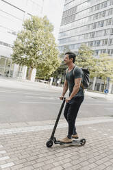 Casual man riding e-scooter in the city - KNSF07675
