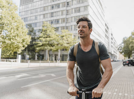 Lässiger Mann fährt E-Roller in der Stadt - KNSF07676