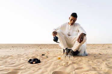 Mann gießt Tee in Gläsern in der Wüste Sahara, Tindouf, Algerien - OCMF01059