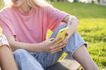 Close-up of young woman holding smartphone on a meadow - AFVF05476