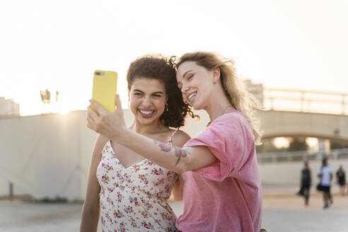 Glückliche Freunde machen ein Selfie im Freien bei Sonnenuntergang - AFVF05496