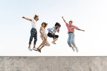 Carefree friends jumping on a concrete wall - AFVF05499