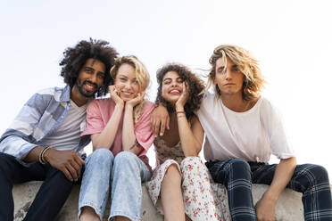 Portrait of happy friends sitting on a wall outdoors - AFVF05511